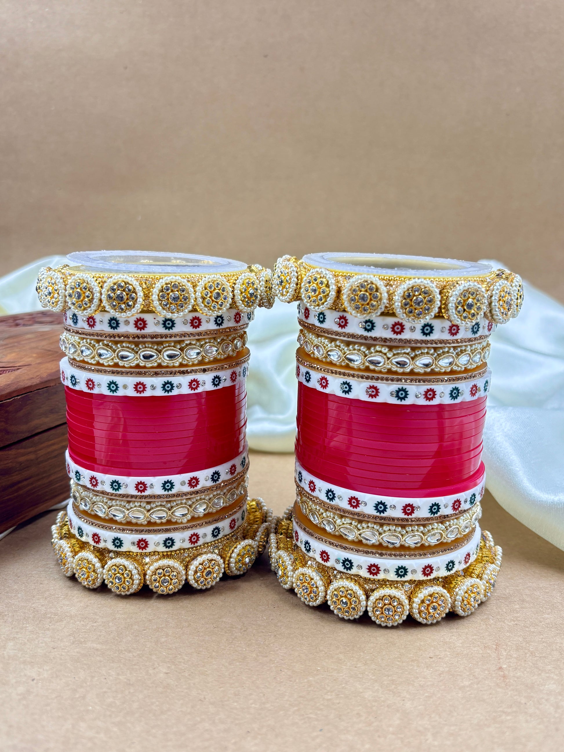 Decorative bangles with red, gold, and multicolor patterns on a beige background by hitesh bangles