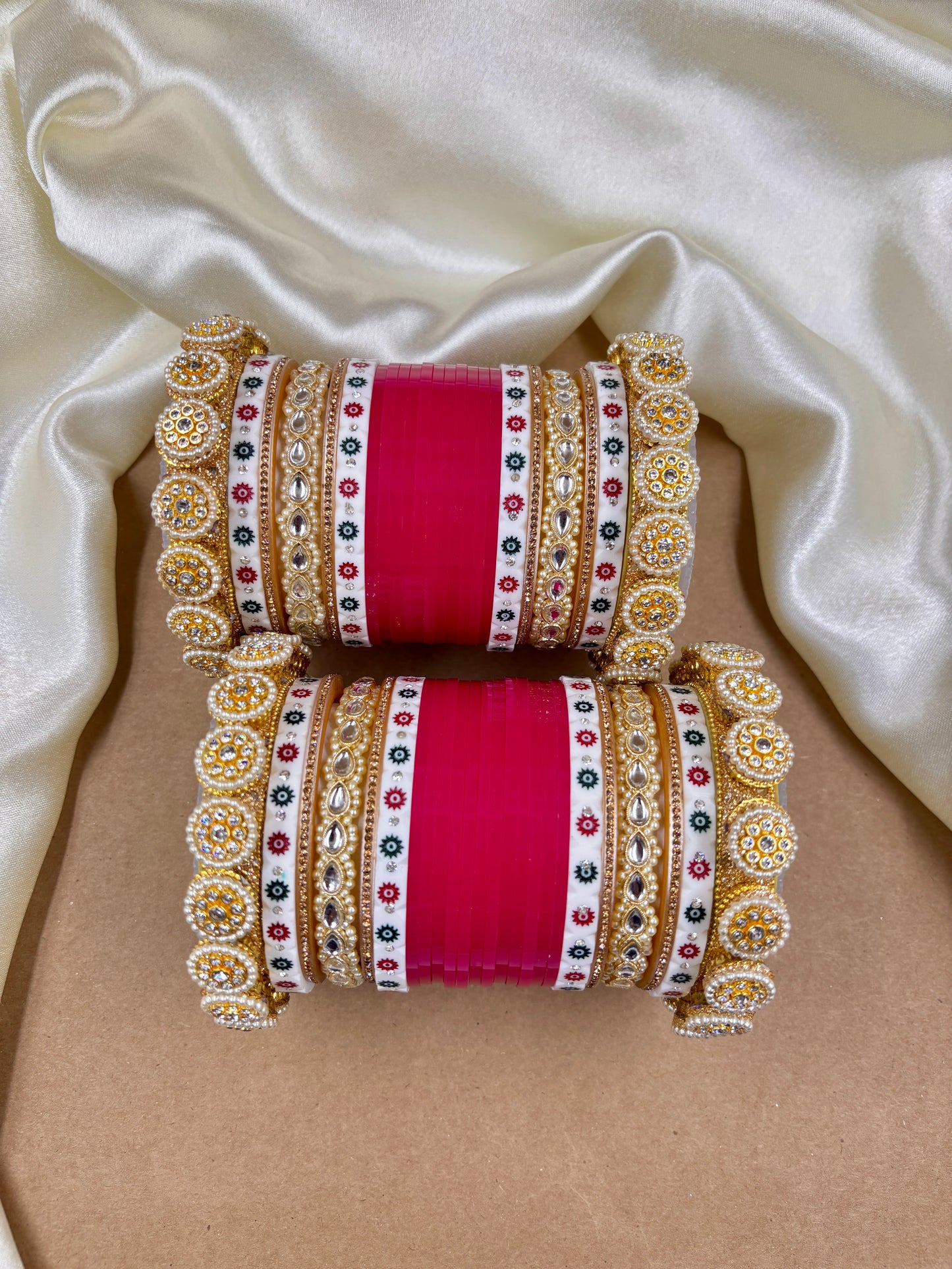 Decorative bangles with intricate designs on a beige fabric background by hitesh bangles