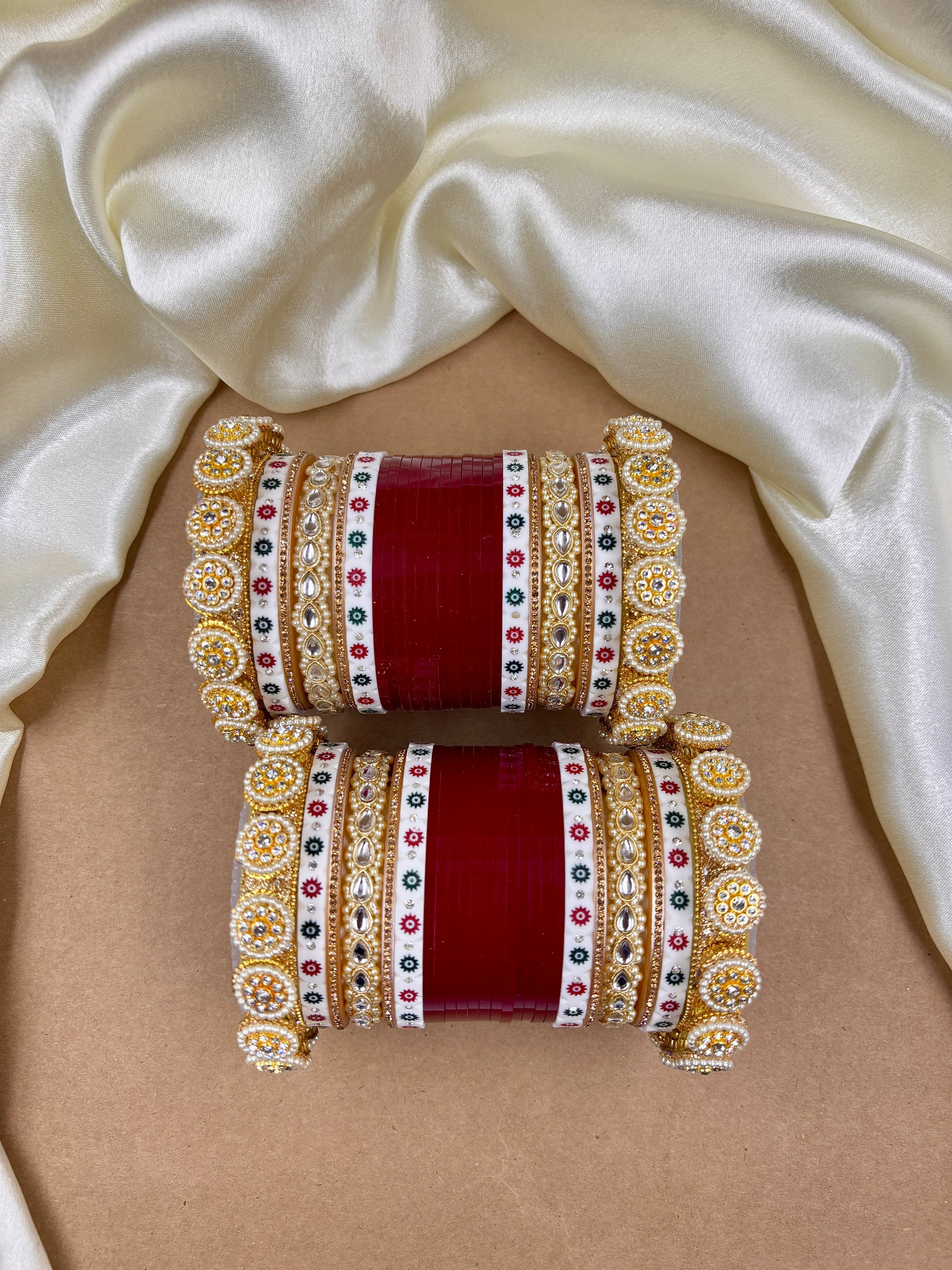 Set of red and gold bangles on a beige fabric background by hitesh bangles
