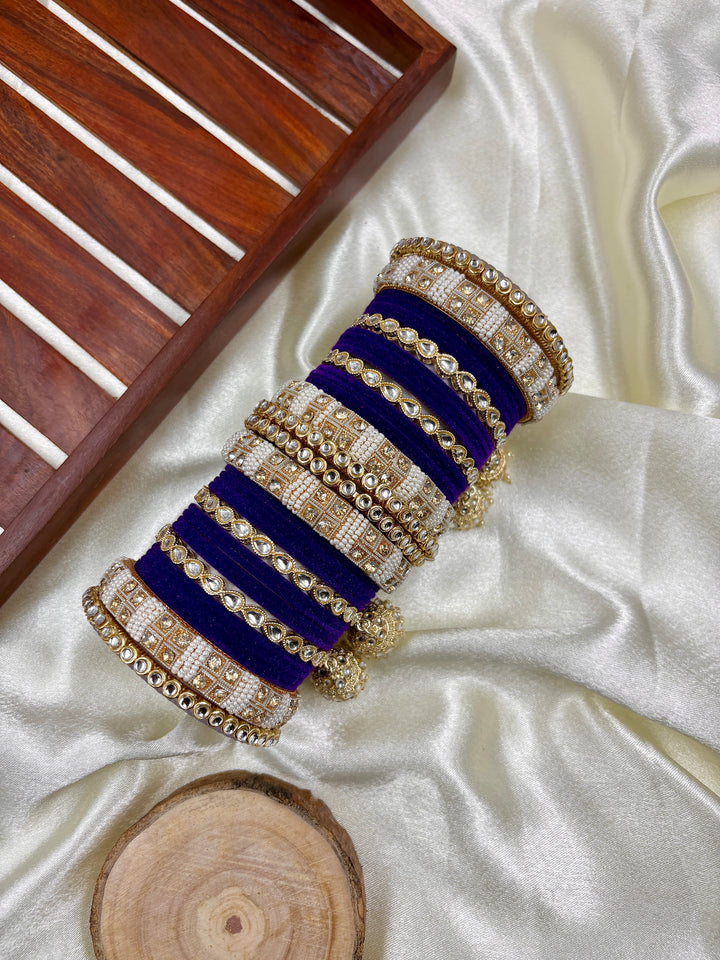 Sapphire Kundan Hanging Bangles Set for women featuring deep blue velvet bangles adorned with intricate kundan work, pearls, and golden jhumkis, styled on a satin background with a wooden tray.