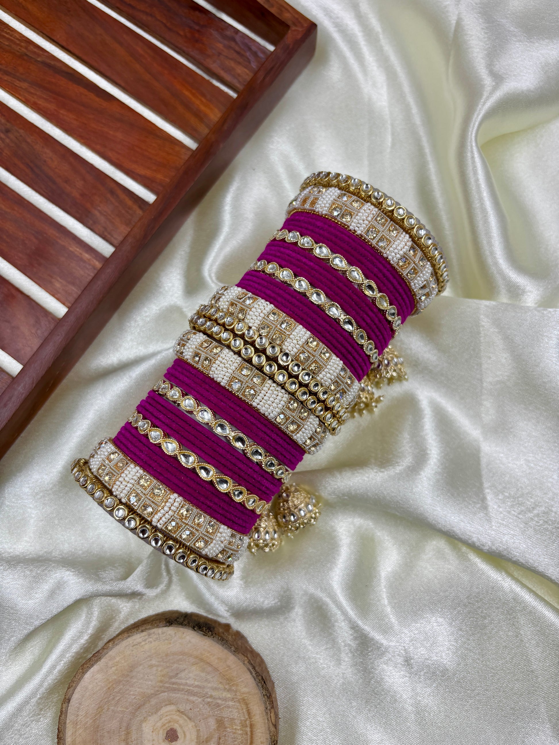 Decorative bangles with purple and gold bands on a white fabric background by hitesh bangles