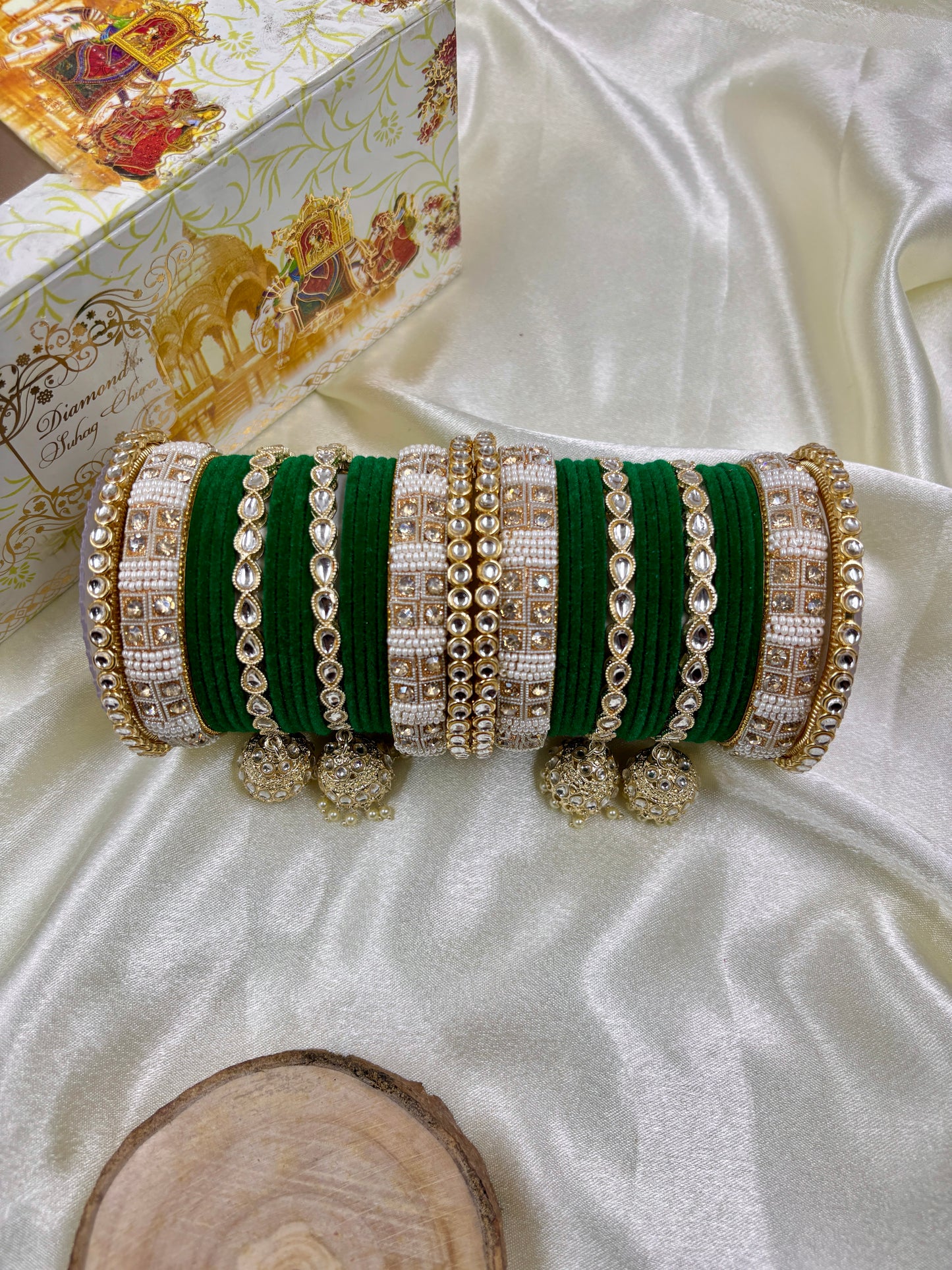 Set of green and gold bangles on a white fabric background by hitesh bangles