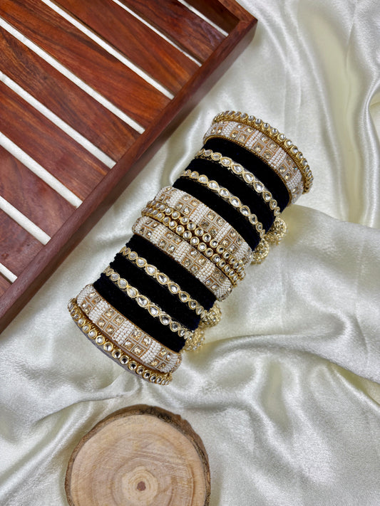 Set of black and gold bangles on a white fabric background by hitesh bangles