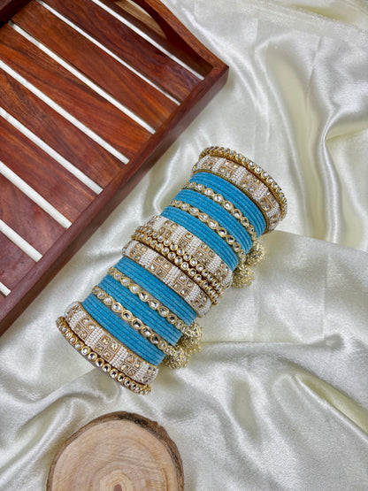 Set of blue and gold bangles on a white fabric with a wooden tray in the background by hitesh bangles