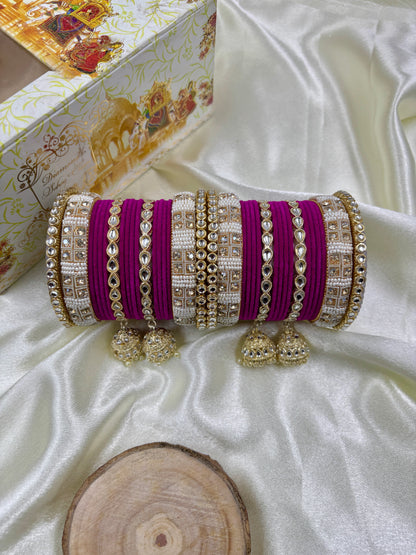 Decorative clutch with purple and gold accents on a white fabric background by hitesh bangles