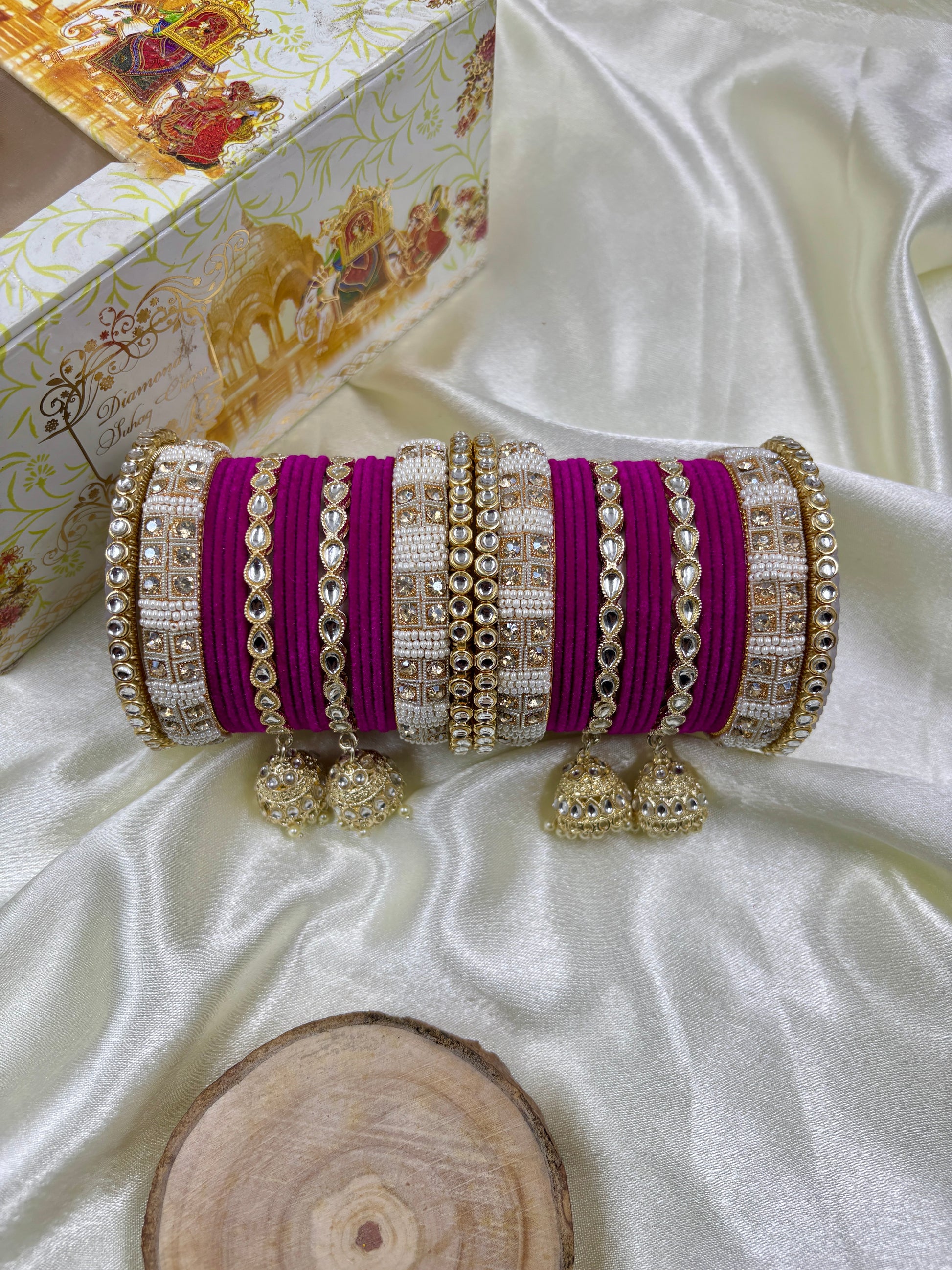 Decorative clutch with purple and gold accents on a white fabric background by hitesh bangles