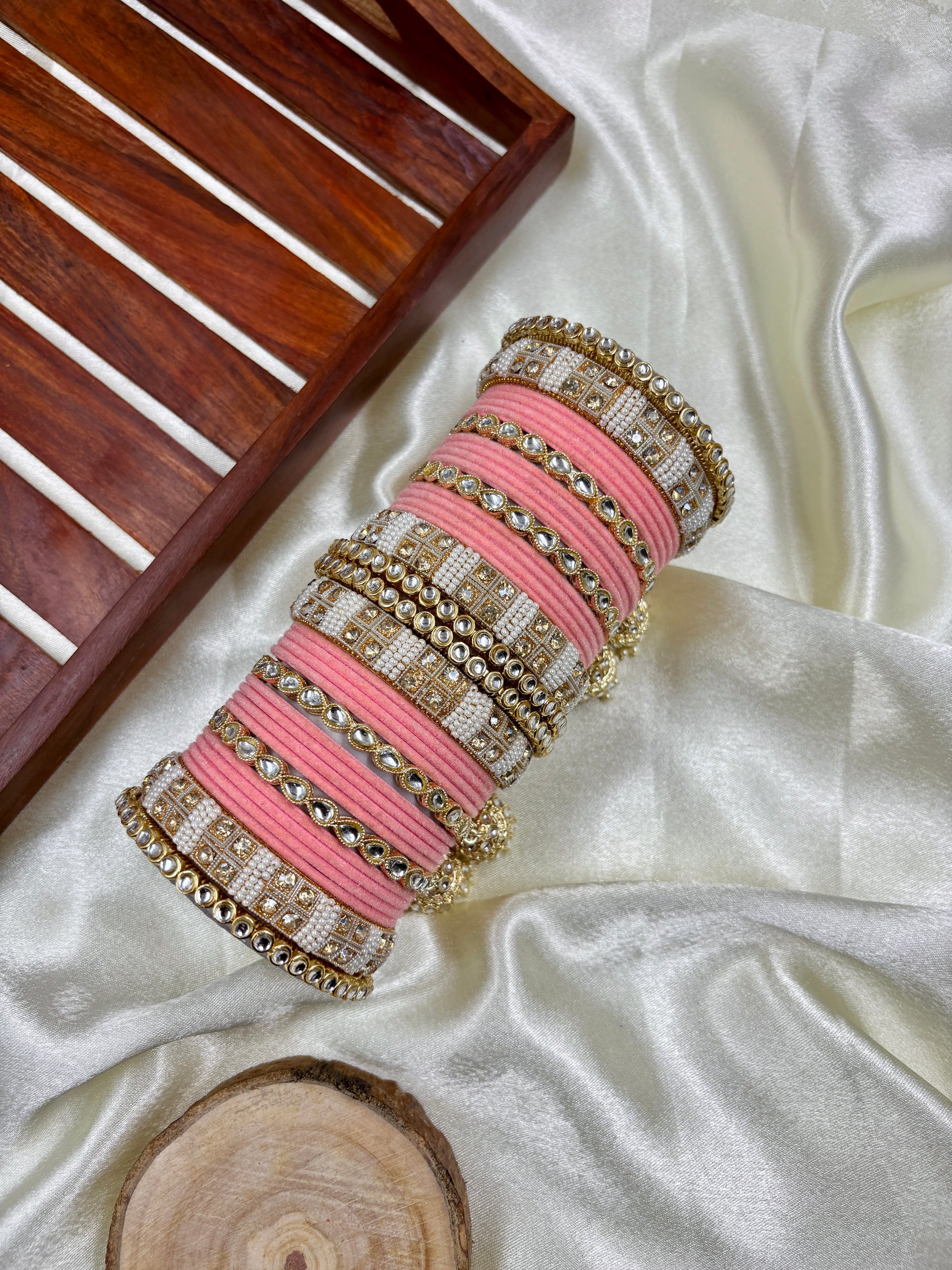 Set of pink and gold bangles on a white fabric background by hitesh bangles
