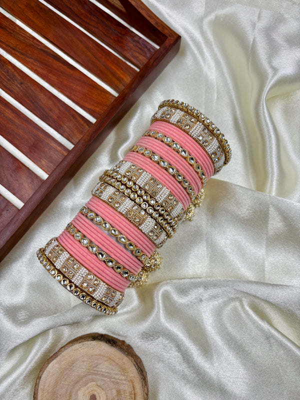 Peach velvet kundan hanging bangle set for women displayed on satin fabric, featuring intricate gold and pearl detailing with jhumki hangings, ideal for bridal and wedding wear.
