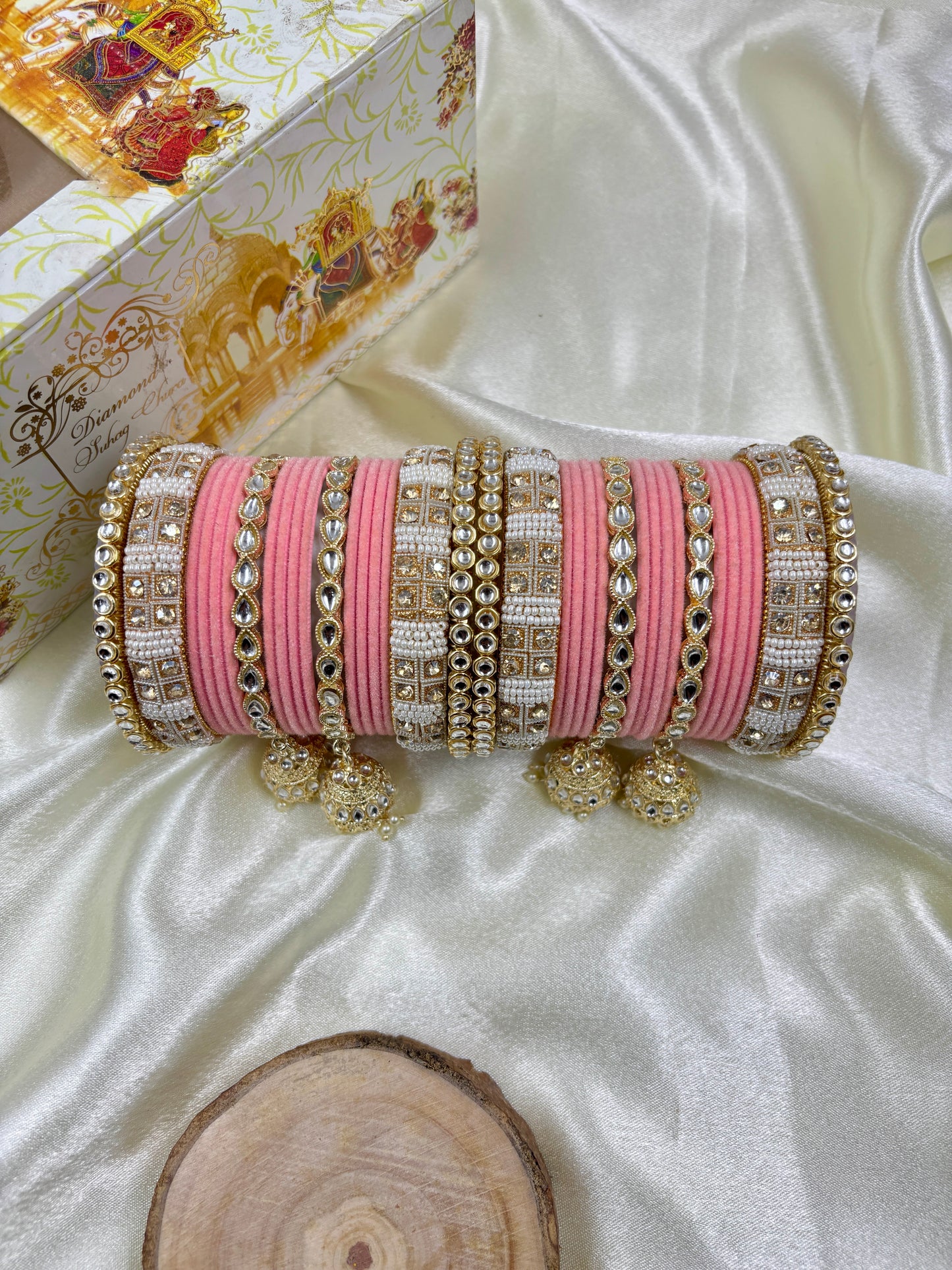 Decorative pink and gold bangles set on a white fabric background by hitesh bangles
