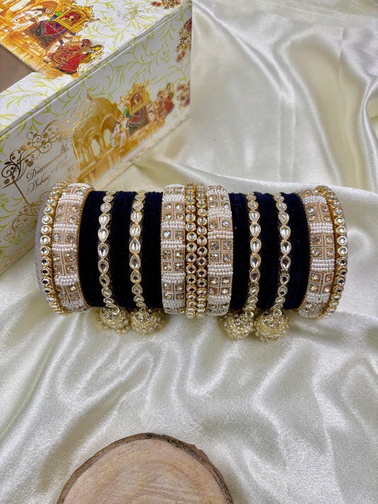 Set of black and gold bangles on a white satin surface with decorative box in the background by hitesh bangles