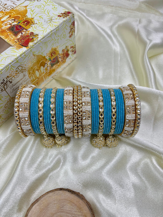 Set of blue and gold bangles on a white satin surface with a decorative box in the background by hitesh bangles