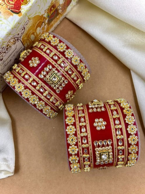 Decorative red and gold bangles on a beige surface by hitesh bangles