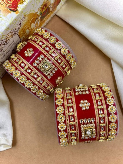 Decorative red and gold bangles on a beige surface by hitesh bangles