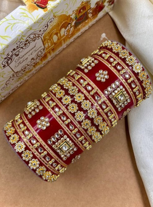 Decorative red and gold box with intricate patterns on a beige surface by hitesh bangles