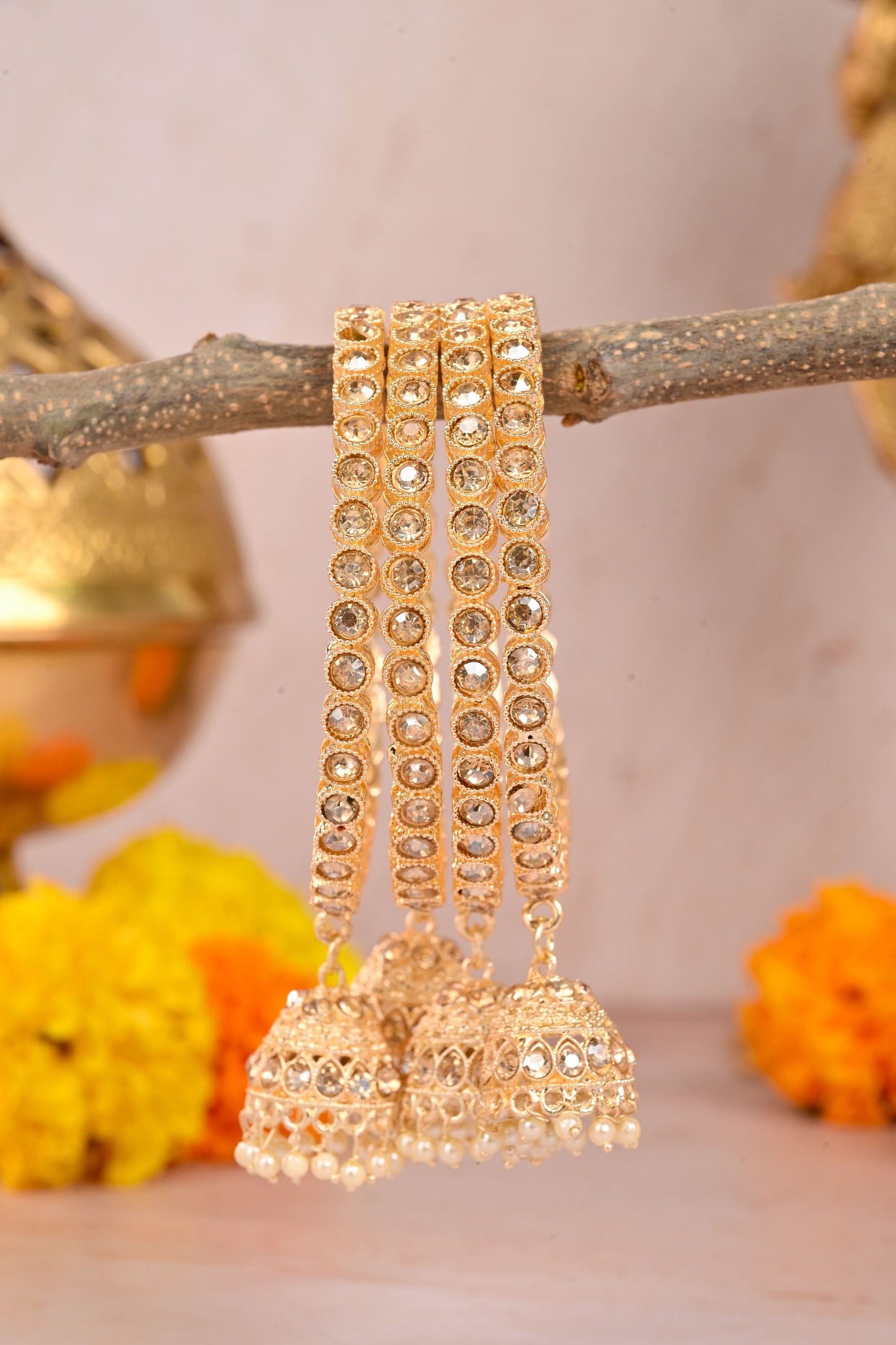 Gold bangles with jhumkas on a branch with a blurred background by hitesh bangles