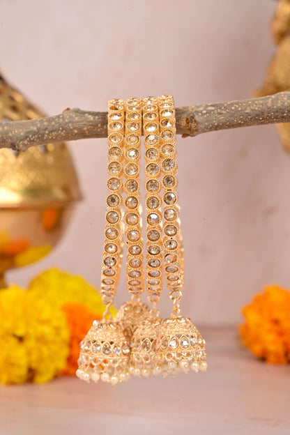 Gold bangles with jhumkas on a branch with a blurred background by hitesh bangles