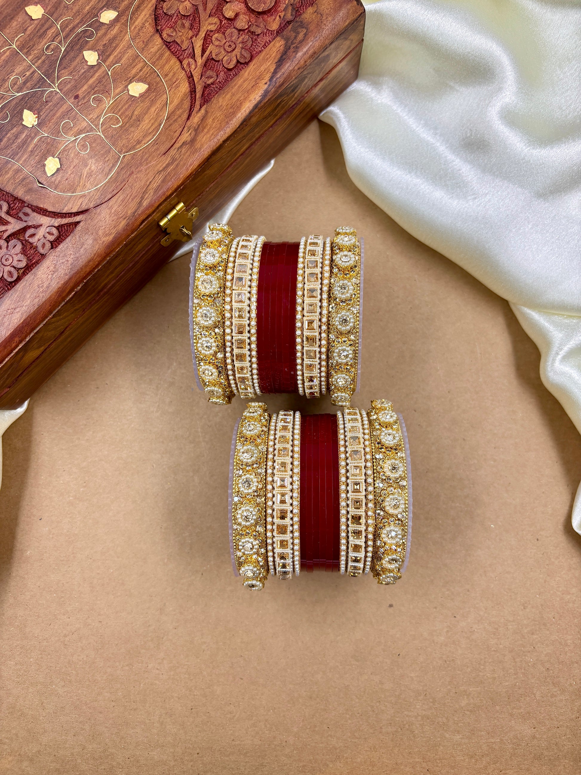Pair of traditional red and gold bridal bangles with intricate stone detailing by hitesh bangles