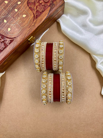 Pair of traditional red and gold bridal bangles with intricate stone detailing by hitesh bangles