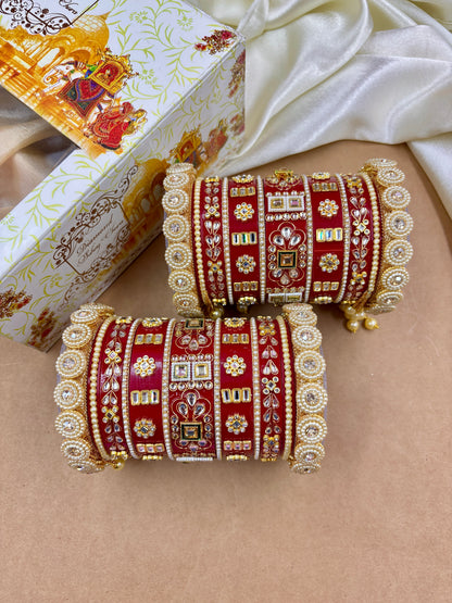 Decorative red and gold bangles on a beige surface with a decorative box in the background by hitesh bangles
