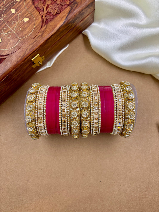 Set of gold and red bangles on a beige surface with a wooden box in the background by hitesh bangles
