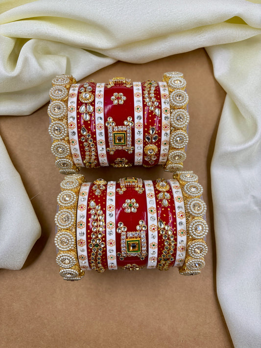 Two red and gold bangles on a beige surface with white fabric by hitesh bangles
