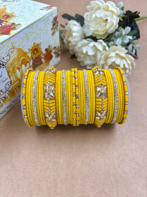 "Vibrant yellow metal velvet bangle set for women adorned with American diamonds and floral motifs, ideal for weddings and festive occasions by Hitesh Bangles."
