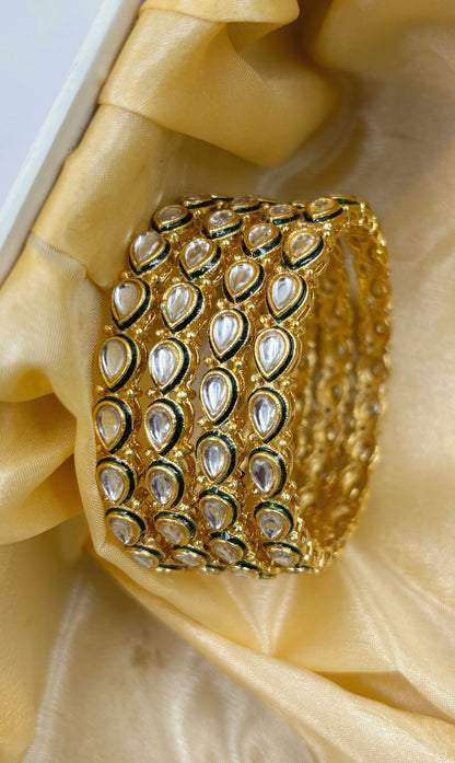 Set of gold bangles on a decorative stand with a patterned box in the background by hitesh bangles
