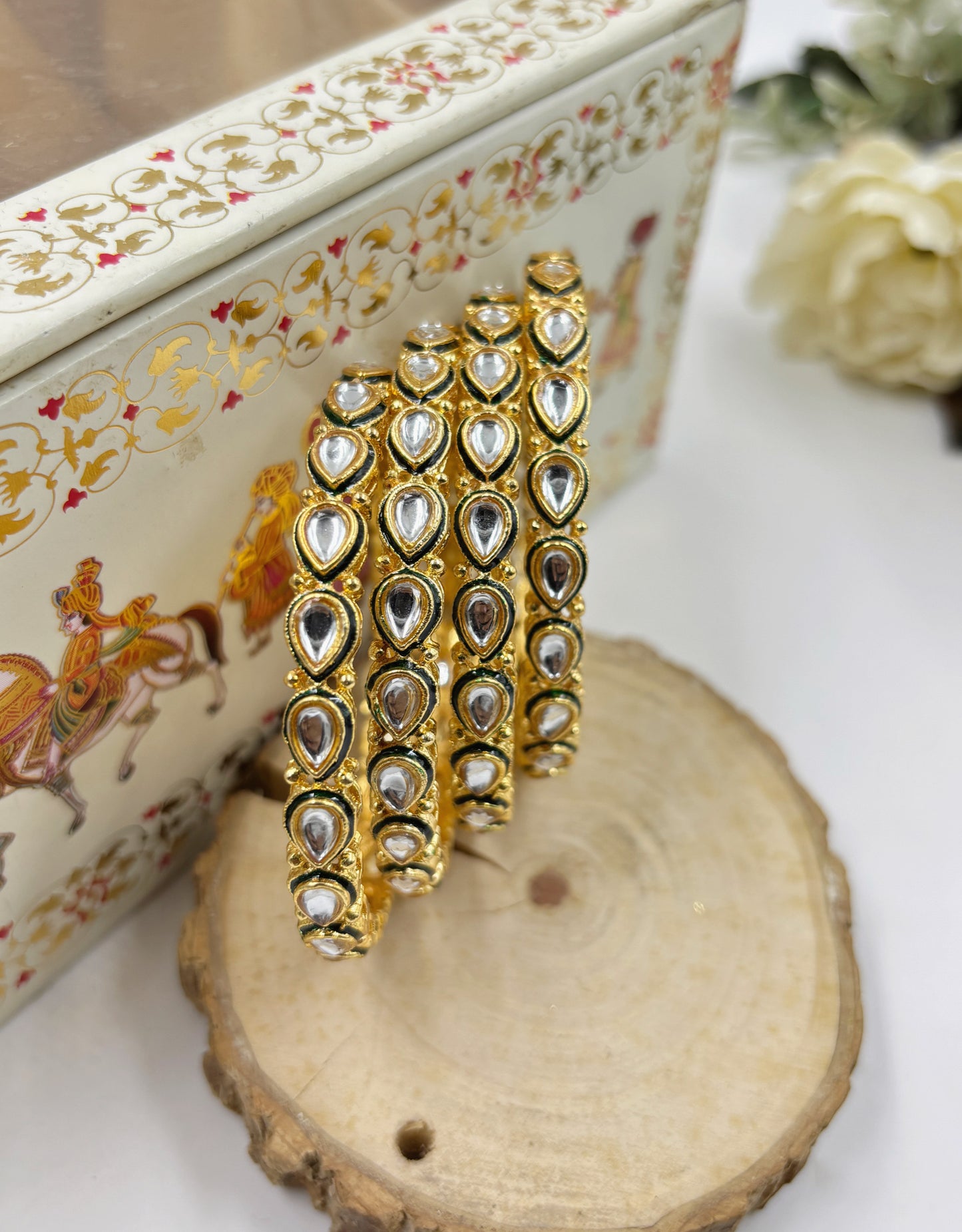 Decorative gold and silver bangles on a wooden surface with a decorative box in the background by hitesh bangles