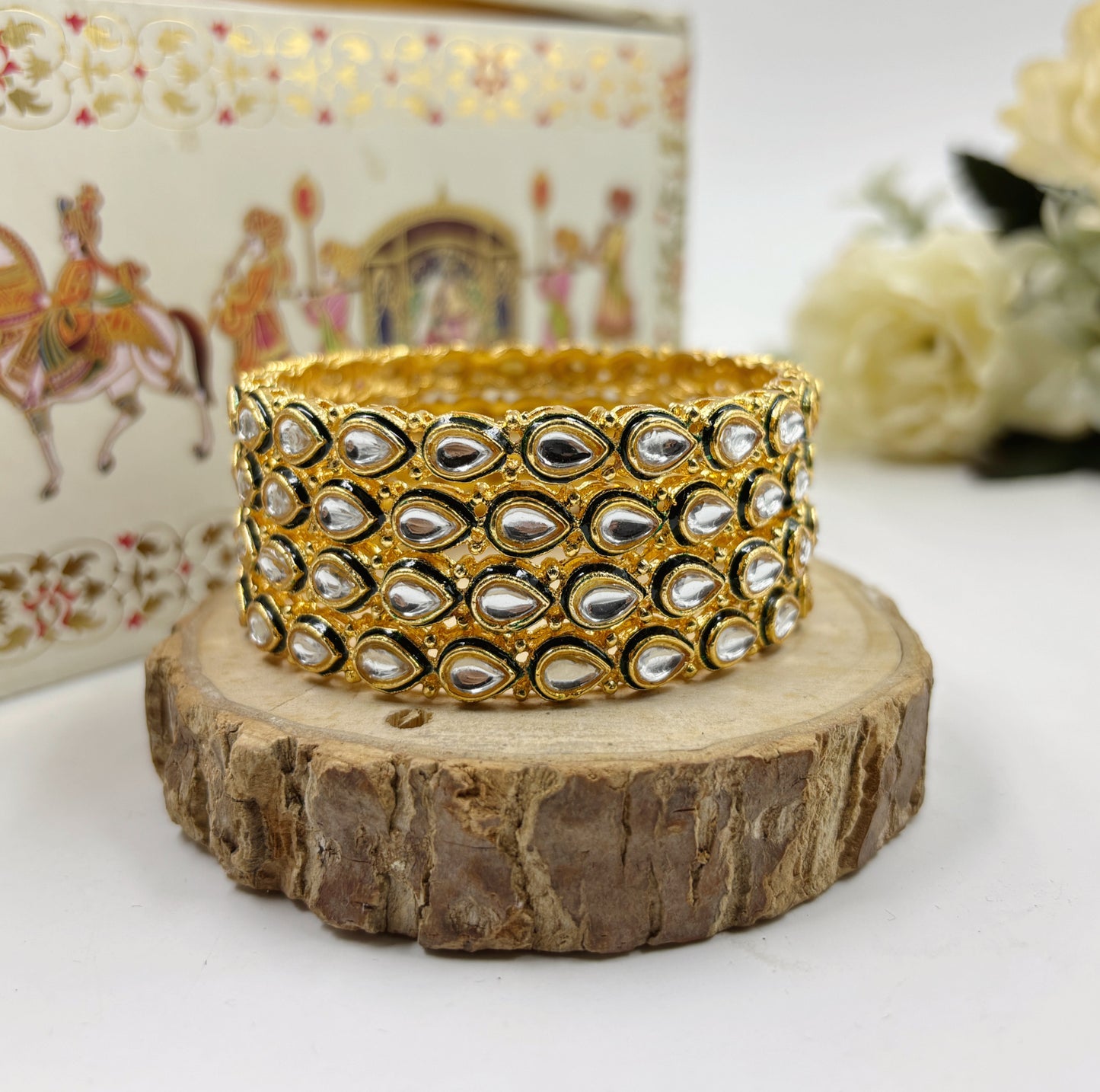 Gold and silver bangles on a wooden stand with a decorative background by hitesh bangles