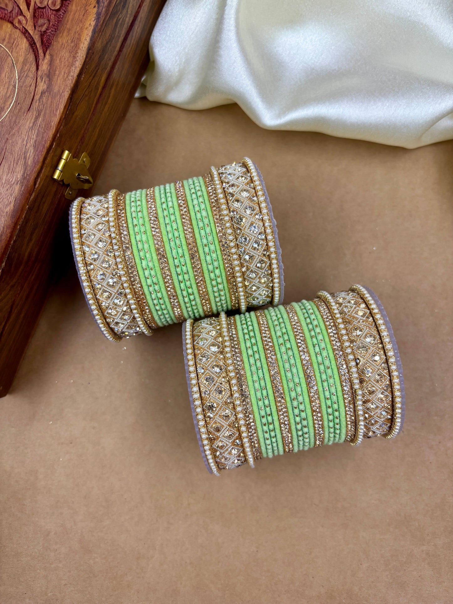 Decorative bangles with green and gold stripes on a brown surface by hitesh bangles