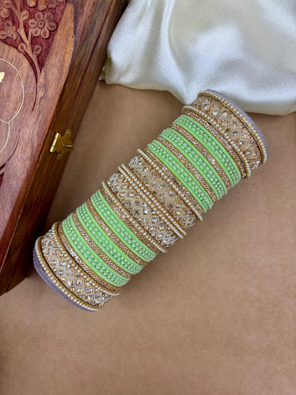 Decorative green bangle with gold and silver details on a person's wrist by hitesh bangles