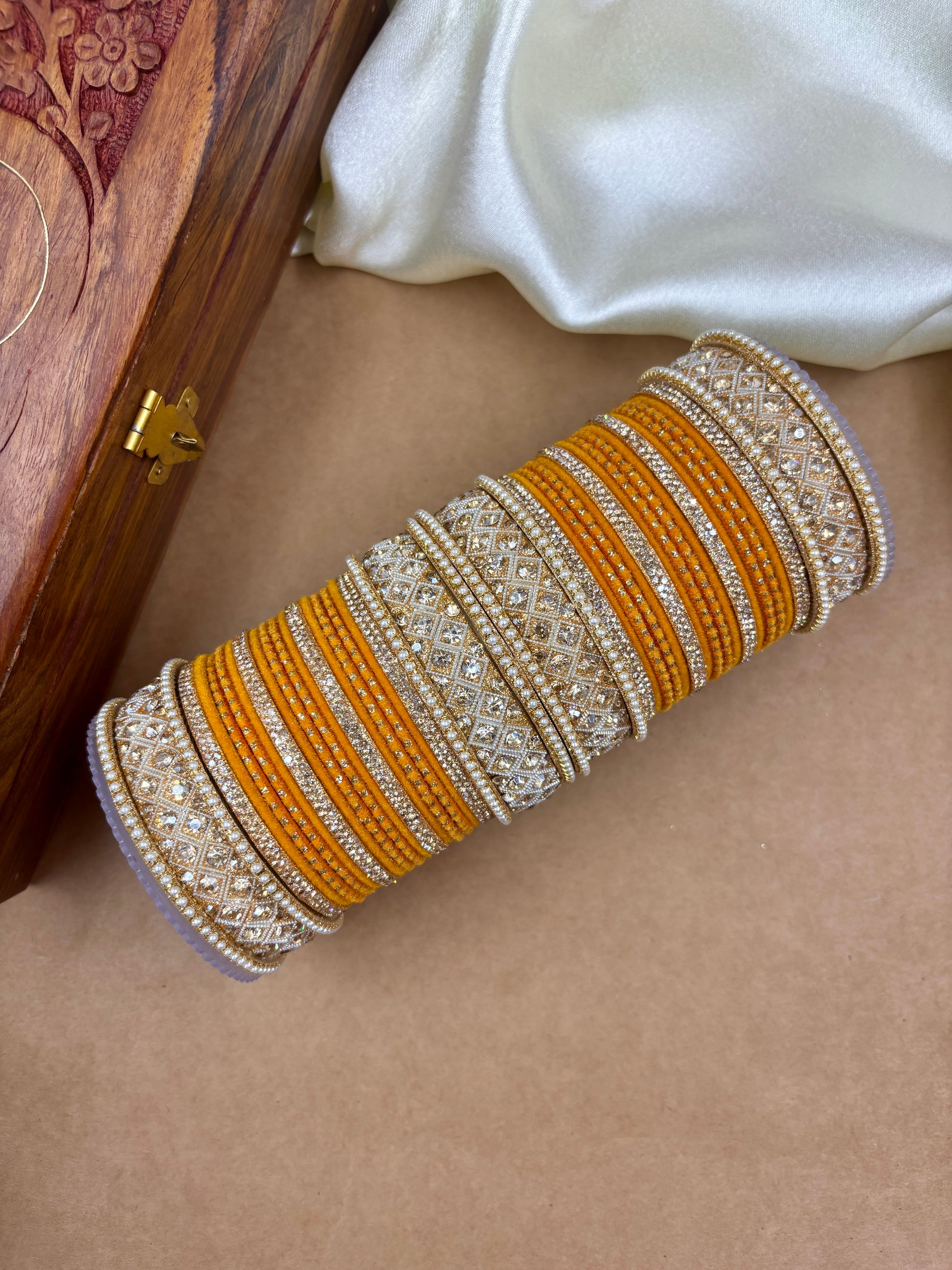 Decorative bangles with gold and silver accents on a beige surface by hitesh bangles