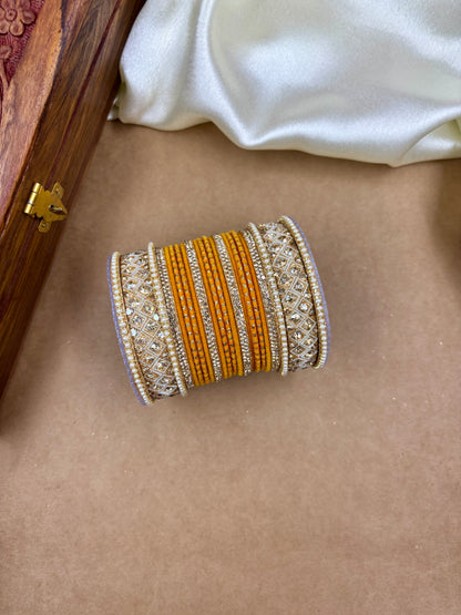 Decorative bangle with orange and gold patterns on a beige surface by hitesh bangles