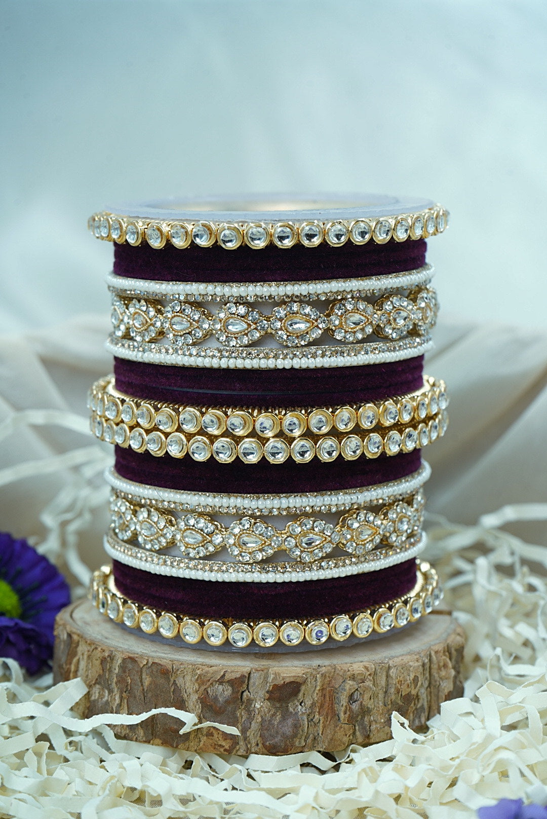 Stack of purple bangles with gold accents on a wooden block by hitesh bangles
