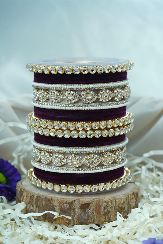 Stack of purple bangles with gold accents on a wooden block by hitesh bangles