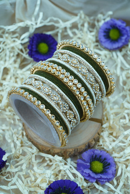 Set of gold and silver bangles on a wooden stand with purple flowers around by hitesh bangles