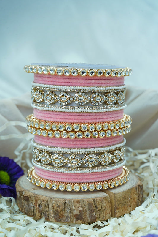 Stack of pink and gold bangles on a wooden stand with a white background by hitesh bangles