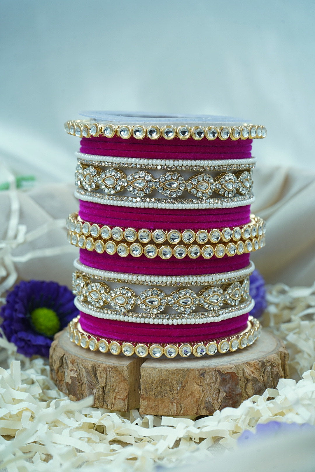 Stack of pink bangles with gold and silver embellishments on a wooden stand by hitesh bangles