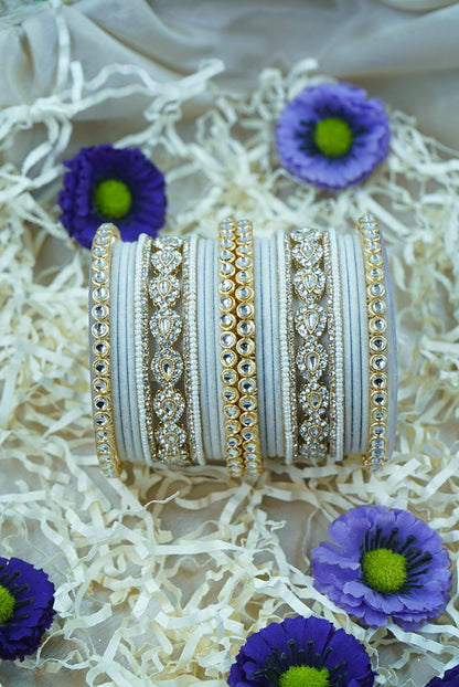 Decorative bangles with intricate designs on a textured surface with purple flowers by hitesh bangles