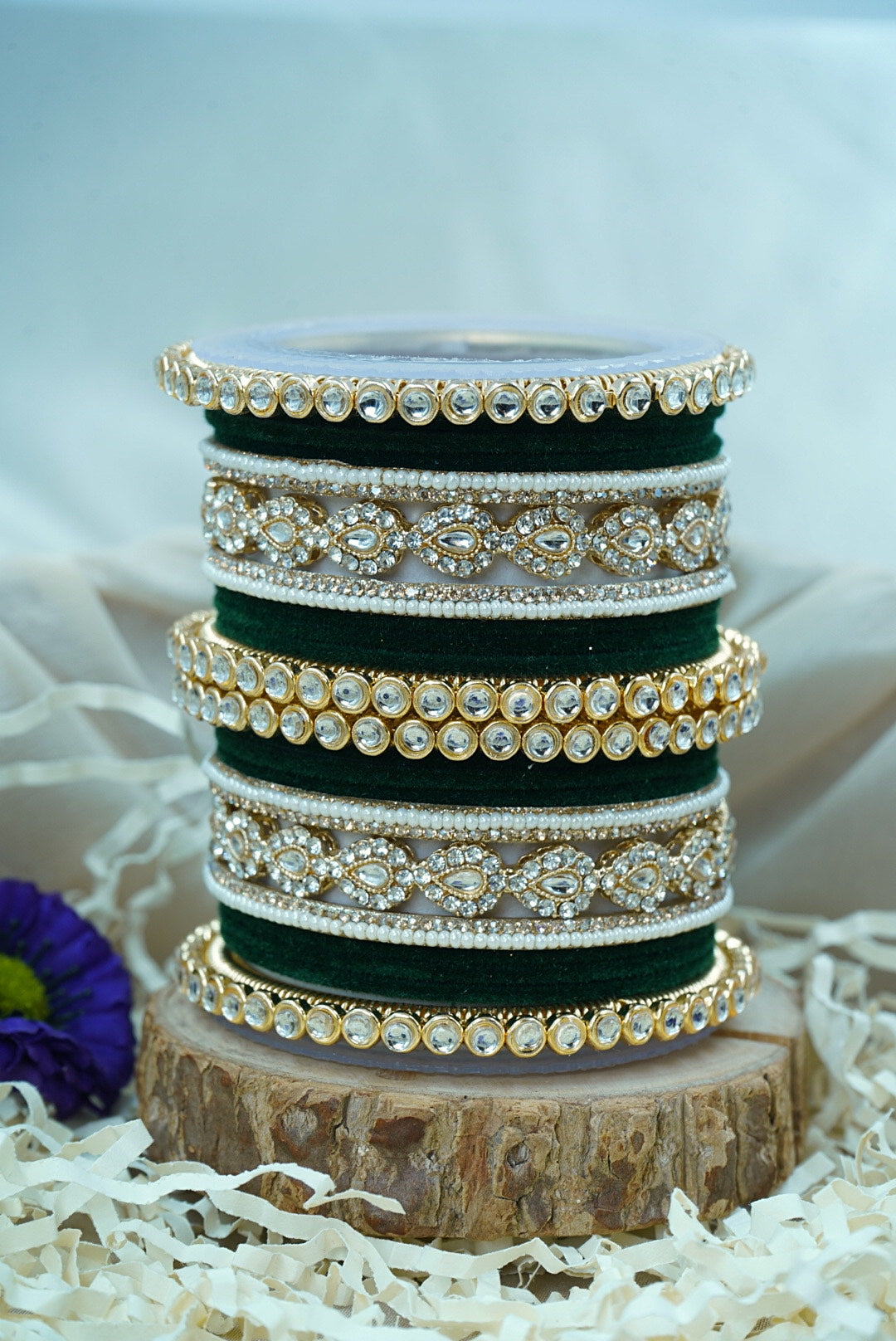 Stack of green and gold bangles on a wooden stand with a blurred background by hitesh bangles