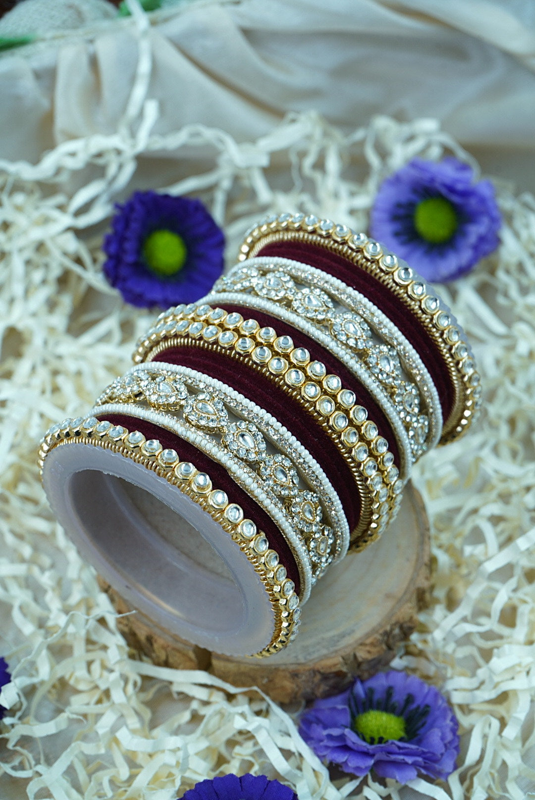 Set of ornate bangles on a decorative surface with purple flowers by hitesh bangles