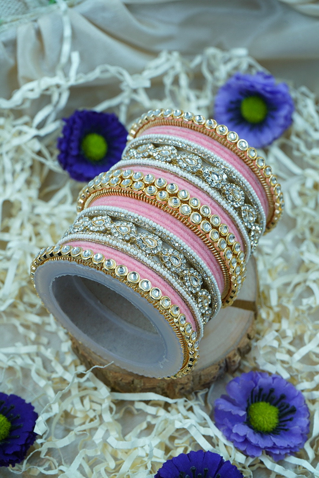 Set of colorful bangles with a wooden stand on a decorative surface with flowers by hitesh bangles