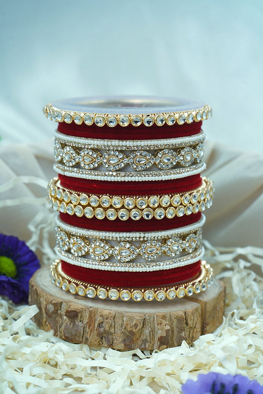 Stack of red and gold bangles on a wooden block with a white background by hitesh bangles