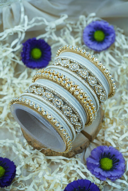 Decorative bangles with intricate designs on a white surface with purple flowers by hitesh bangles