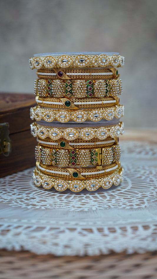 Stack of gold and diamond bangles on a textured surface by hitesh bangles