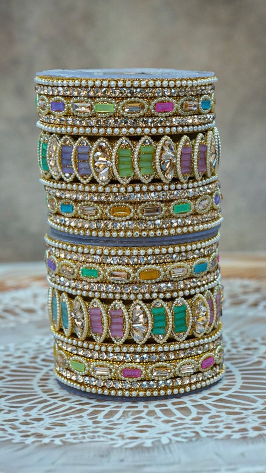 Stack of colorful bangles with intricate designs on a textured surface by hitesh bangles