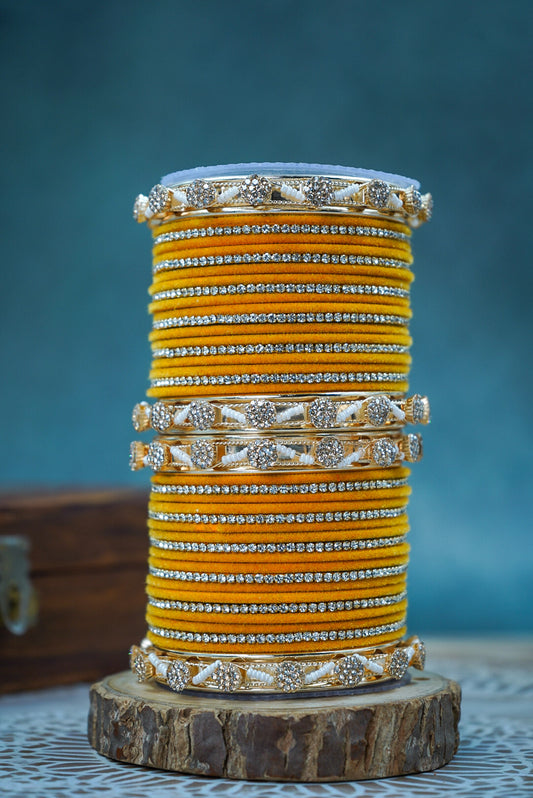 Stack of yellow bangles with silver accents on a wooden stand against a blue background by hitesh bangles