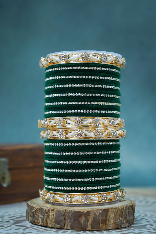 Stack of green bangles with gold and silver accents on a wooden stand against a blue background by hitesh bangles