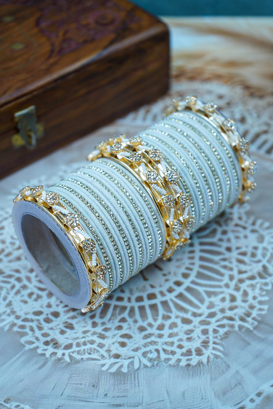 Set of gold and silver bangles on a white doily with a wooden box in the background by hitesh bangles