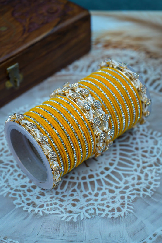 Yellow bangles with silver accents on a white doily with a wooden box in the background by hitesh bangles